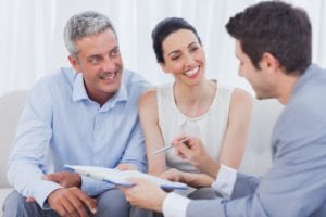 man with a clipboard speaking with a smiling couple