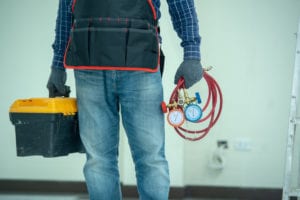 hvac-technician-holding-box-and-pressure-hoses